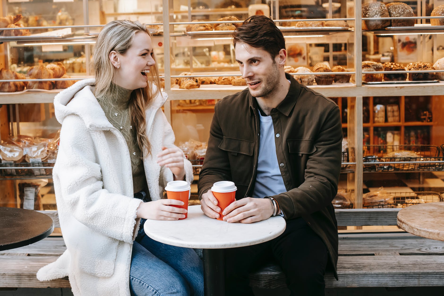 laughing woman talking with boyfriend during date in bakery